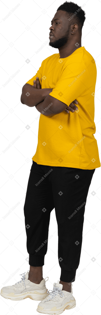 Vue de trois quarts d'un jeune homme à la peau foncée en t-shirt jaune croisant les bras