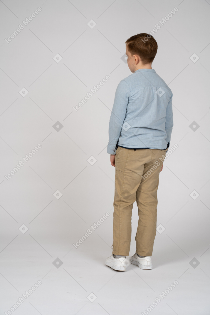 Мальчик стоит спиной к камере