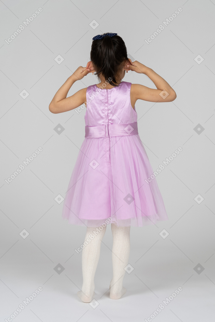 Girl in pink dress pulling her ears