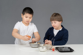 Zwei kleine jungen üben das backen