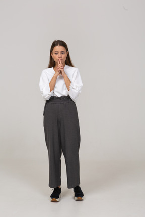 Vista frontal de uma jovem pensativa com roupa de escritório, de mãos dadas