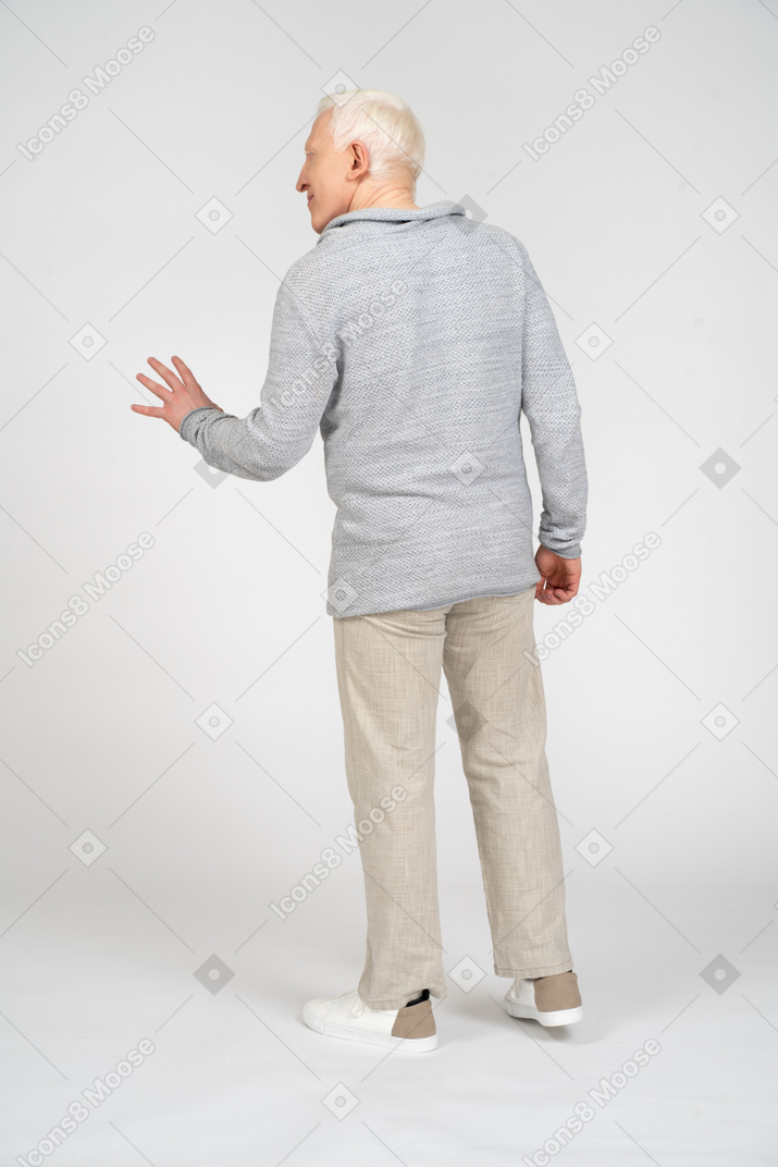 Back view of man waving with his left hand