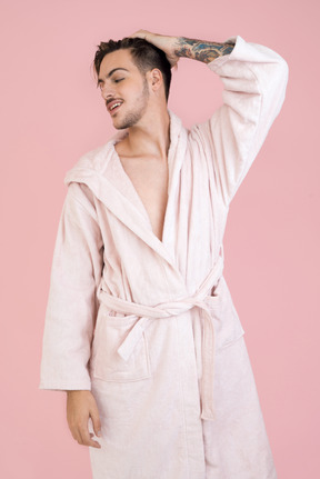 Attractive young man holding his head aside and adjusting his hair