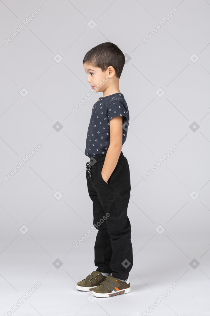 Side view of a cute boy posing with hands in pockets