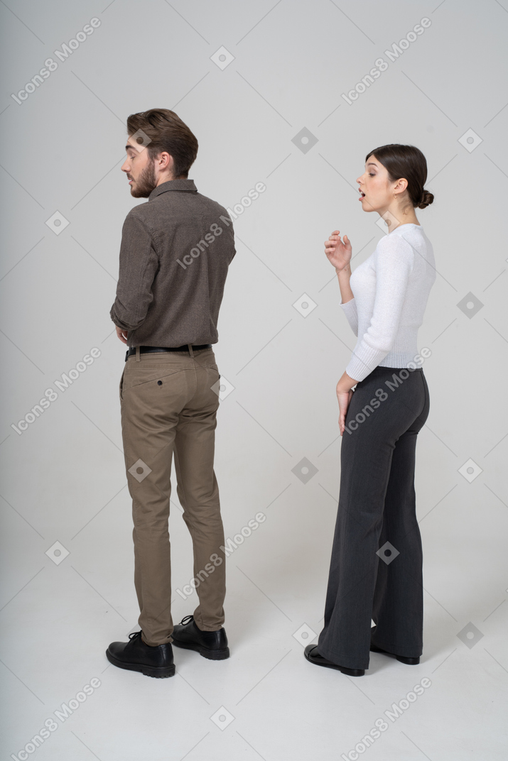 Three-quarter back view of a yawning young couple in office clothing