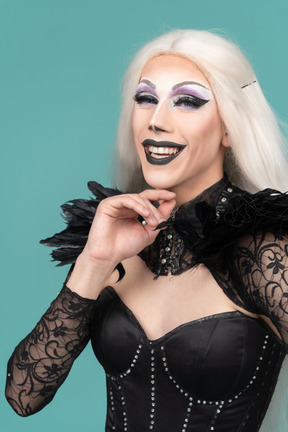 Joyful dragqueen holding hand on chin