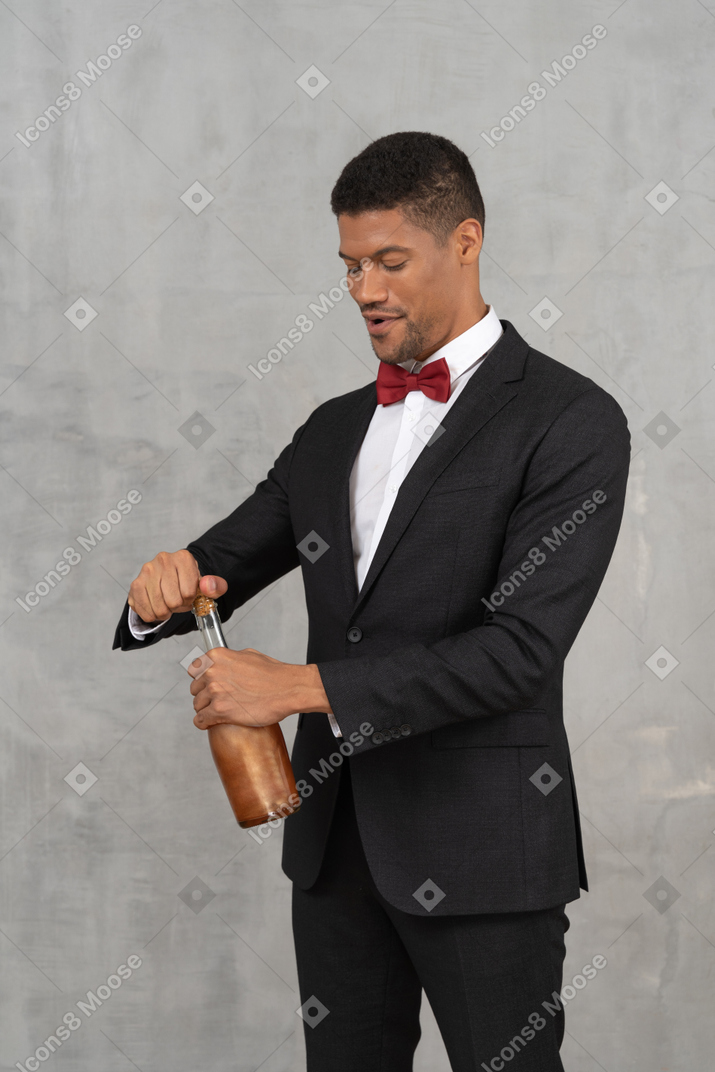 Young man getting cork out of a liquor bottle