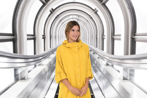 A woman in a yellow raincoat standing in a tunnel