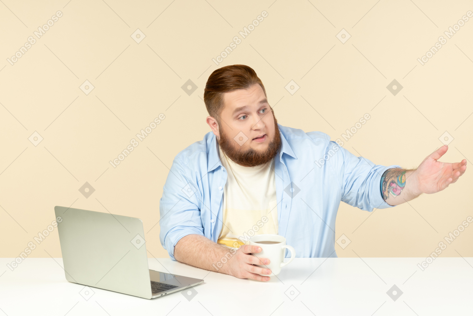 Young overweight man sitting in front of laptop and having tea