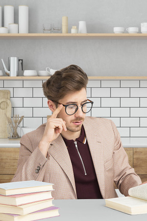 A man sitting at a table with a stack of books