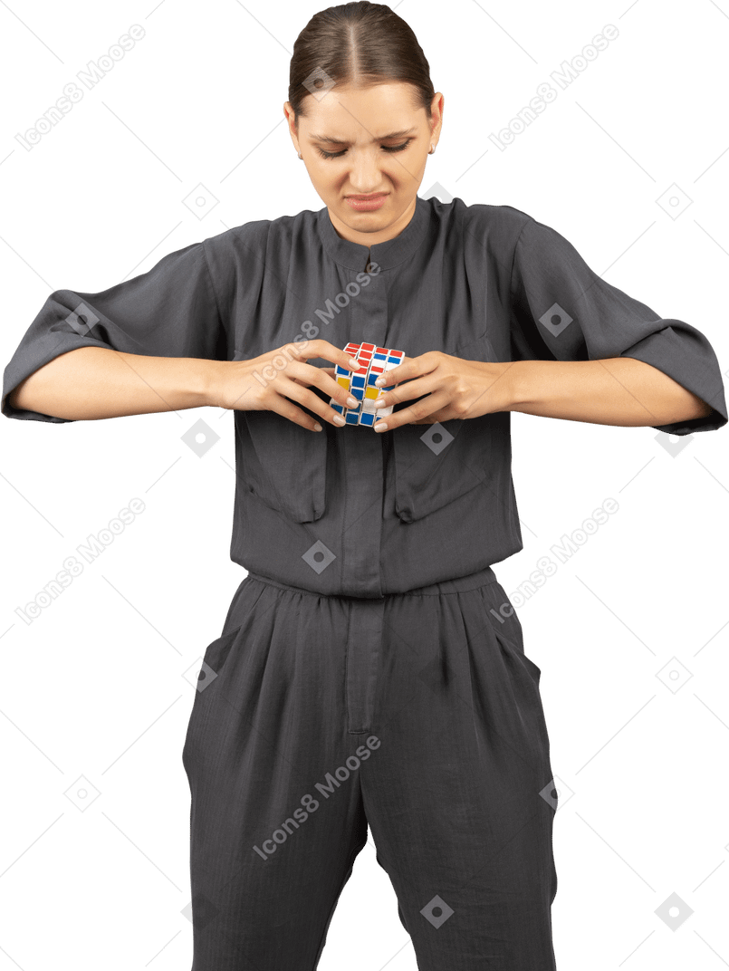 Vista frontale di una giovane donna in tuta che cerca di risolvere il puzzle del cubo di rubik
