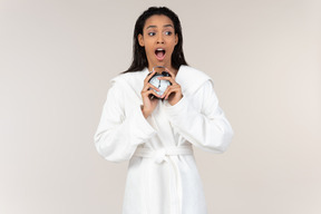 Black woman in white bathrobe going about her morning routine