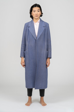 Donna scettica in cappotto blu con sopracciglio alzato