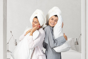 Women standing next to each other and hugging pillows