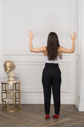 Back view of young woman raising hands