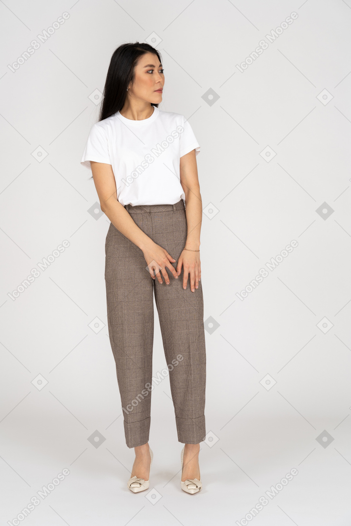 Vista frontal de una joven sospechosa en pantalones y camiseta mirando a un lado