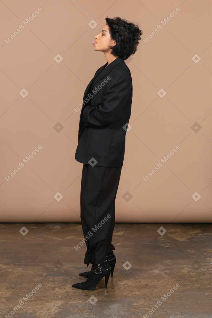 Side view a female businesswoman in a black suit showing tongue