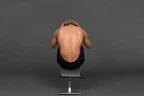 Vista posteriore di un uomo afro a torso nudo che fa crunch