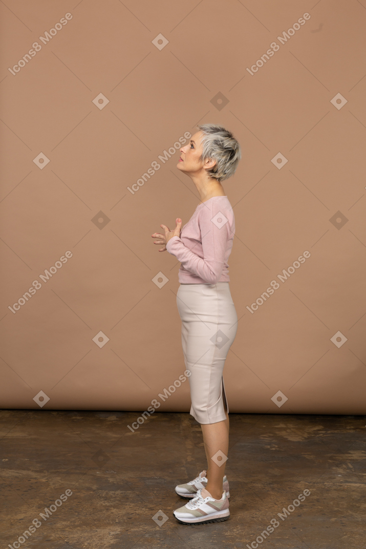 Vista lateral de una mujer en ropa casual posando con las manos en el pecho