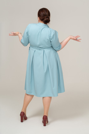 青いドレスを身振りで示す女性の背面図