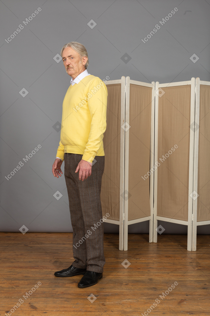 Vista de tres cuartos de un anciano inmóvil mirando a la cámara