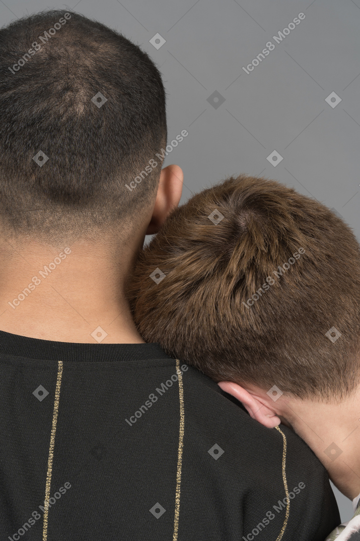 Vista traseira do jovem inclinando a cabeça no ombro do namorado