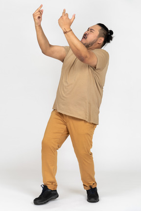 Anxious young man raising hands and looking up