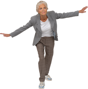 Vista frontal de uma senhora idosa de terno em pé com os braços estendidos