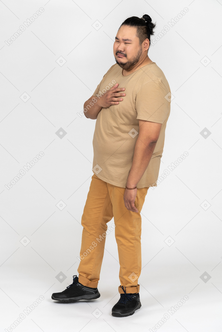 Sad asian man standing with hand on his chest
