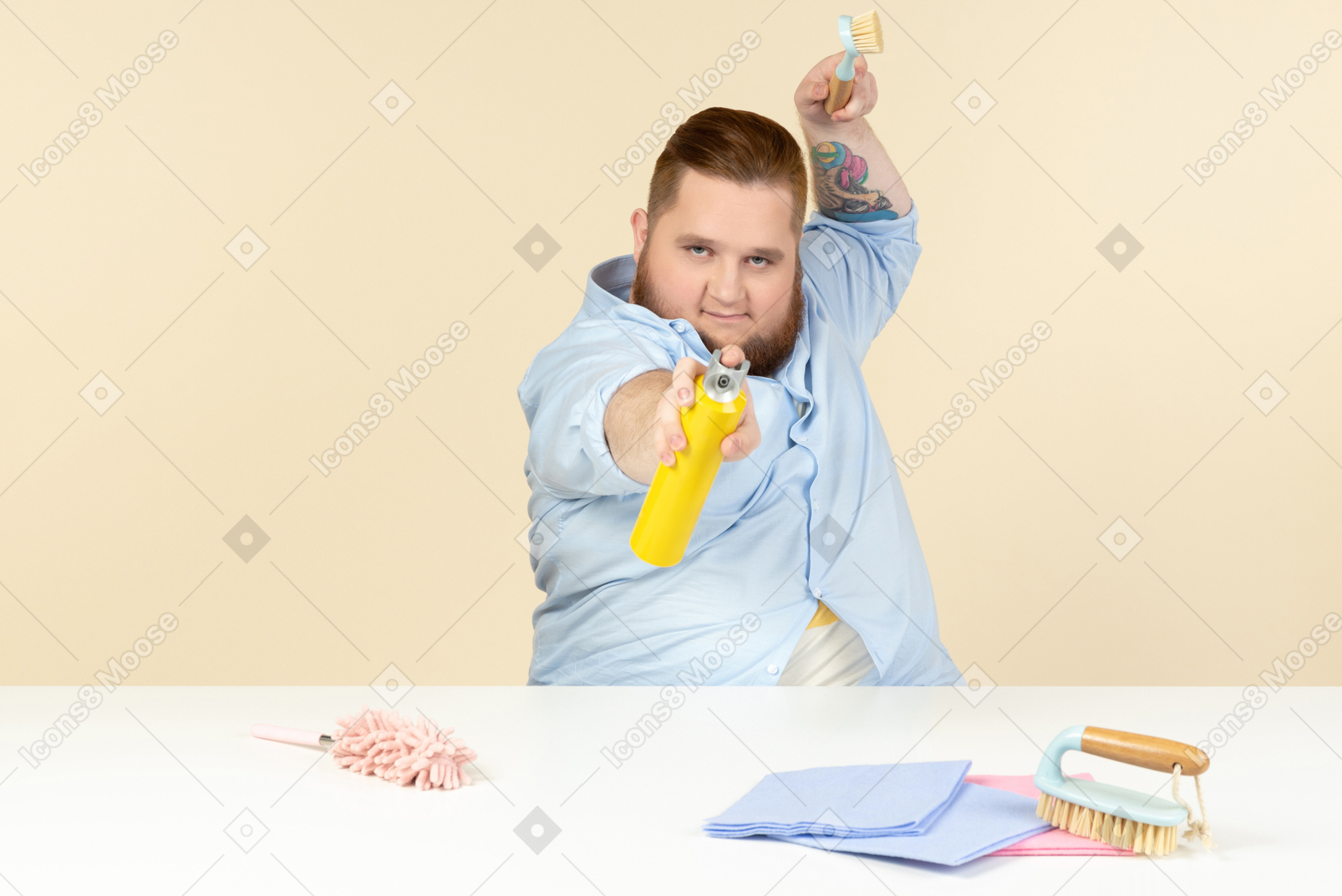 Young overweight man sitting at the table and holding cleaning equipment