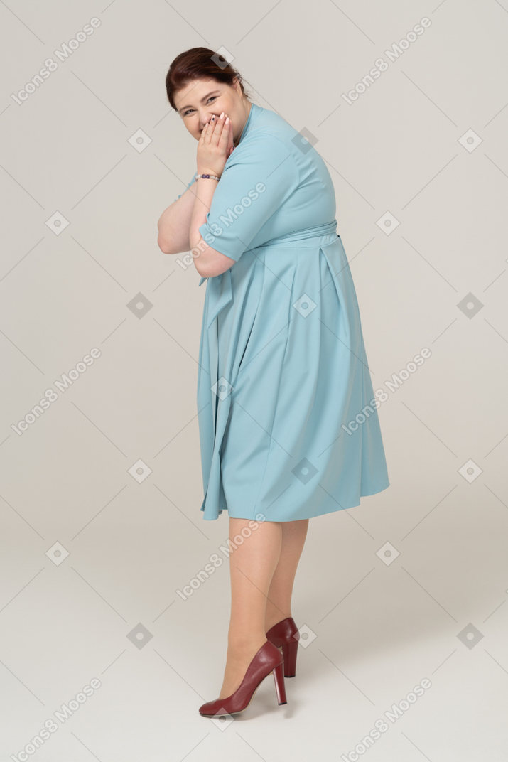 カメラを見て青いドレスを着た幸せな女性の側面図