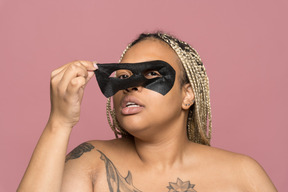 Mujer afroamericana regordeta quitando una máscara de ojo negro