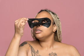 Plump african-american woman removing a black eye mask