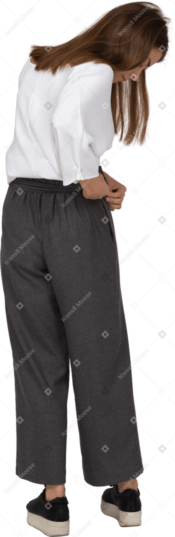 Vista posterior de una señorita en ropa de oficina ajustando sus pantalones