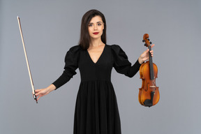 Gros plan d'une jeune femme en robe noire tenant le violon et l'archet