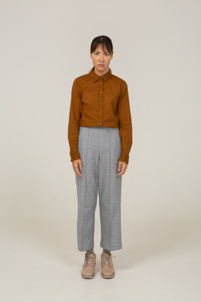 Front view of a worried young asian female in breeches and blouse standing still