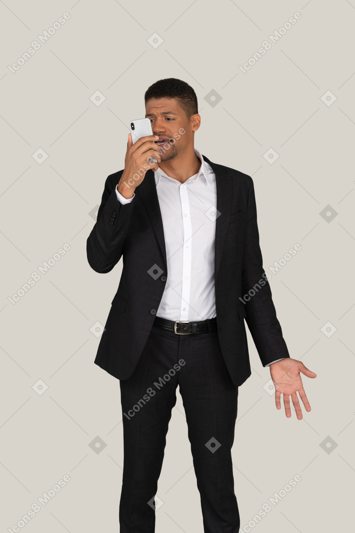 Angry young office worker saying something to the phone