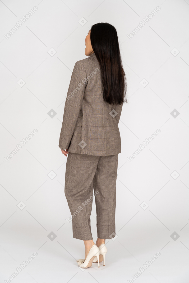茶色のビジネススーツで驚いた若い女性の4分の3の背面図