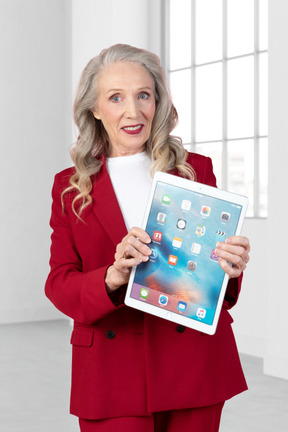 A woman in a red suit holding an ipad