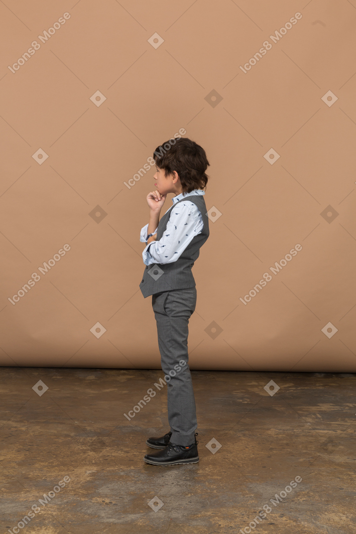 Vue latérale d'un garçon mignon réfléchi en costume