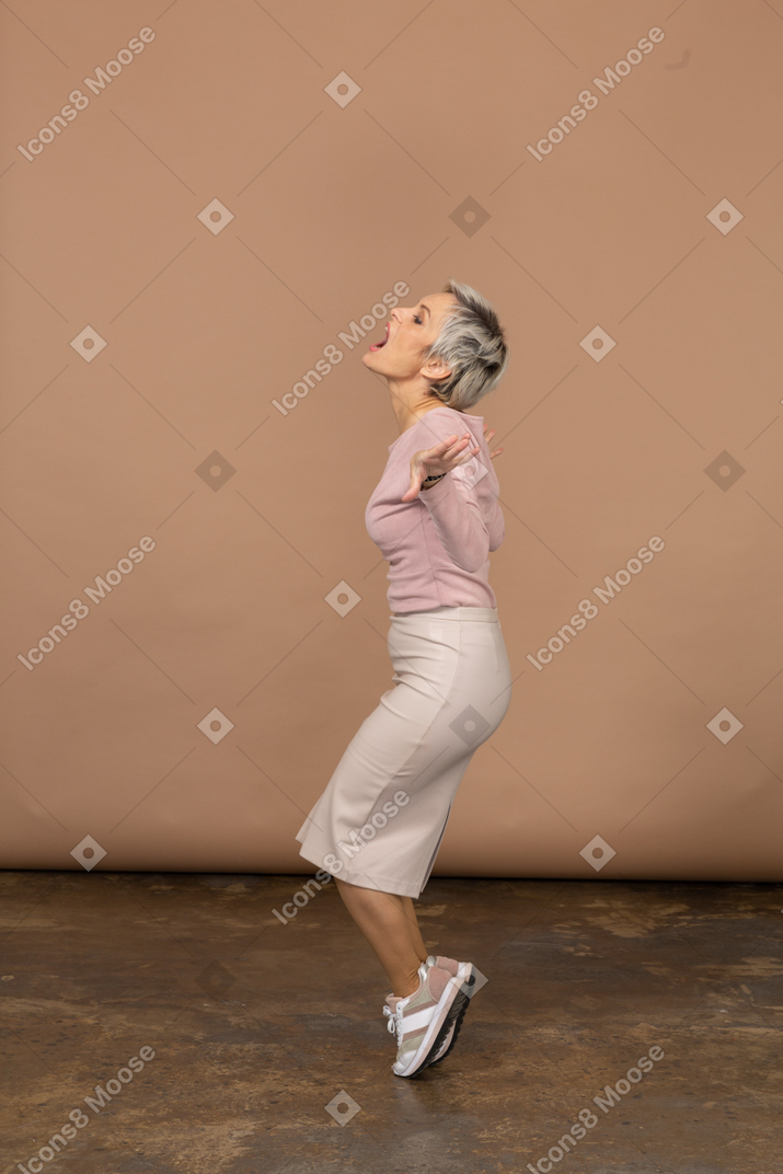 一个情绪化的女人穿着休闲服站在脚趾和外展手臂的侧视图
