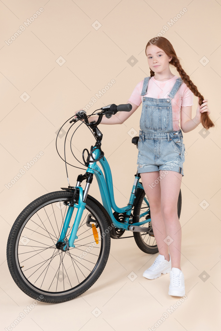 Teenage girl standing near blue bicycle