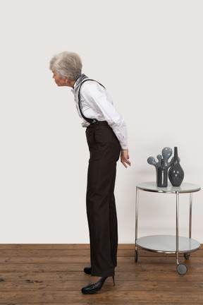 Side view of a curious old lady in office clothing leaning forward