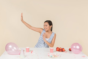 Mujer asiática joven contenta sentada en la mesa de cumpleaños