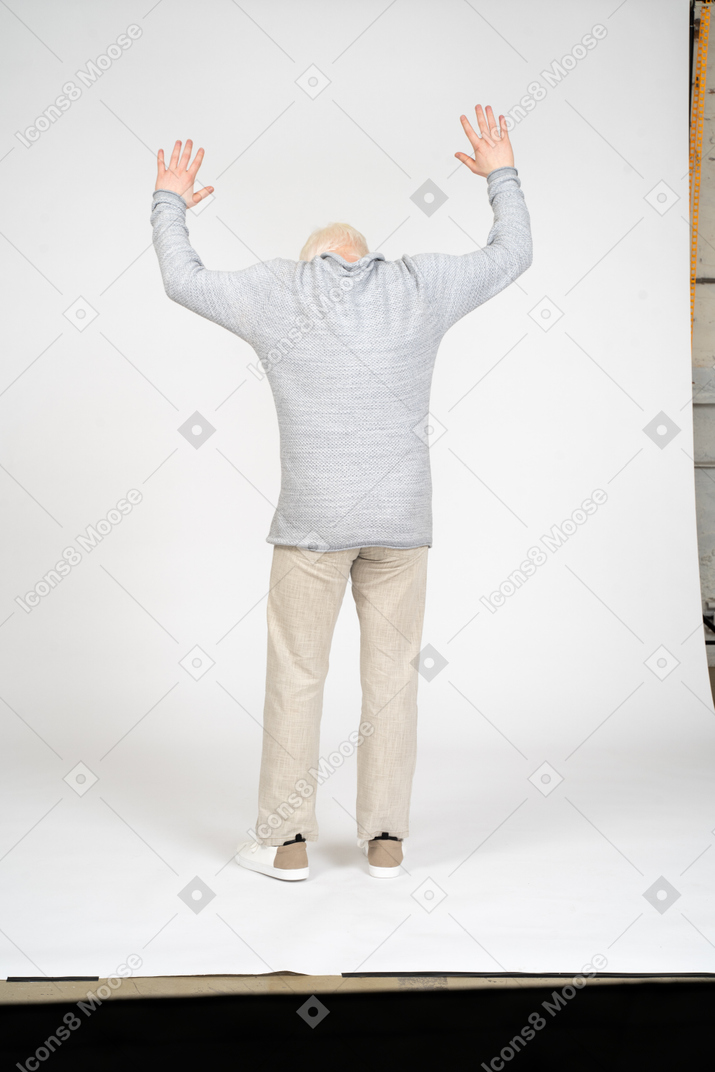 Homem de pé com os braços levantados e de costas para a câmera