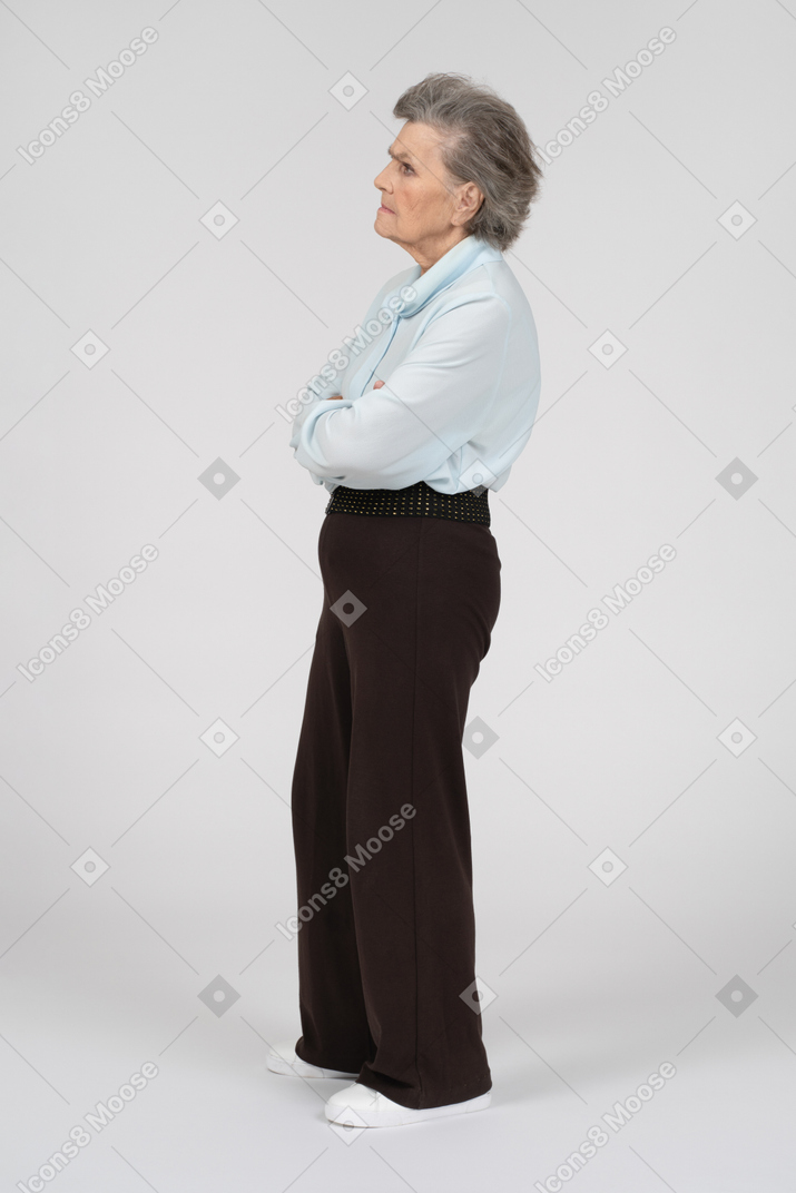 Вид сбоку на пожилую женщину, хмурящуюся со сложенными руками