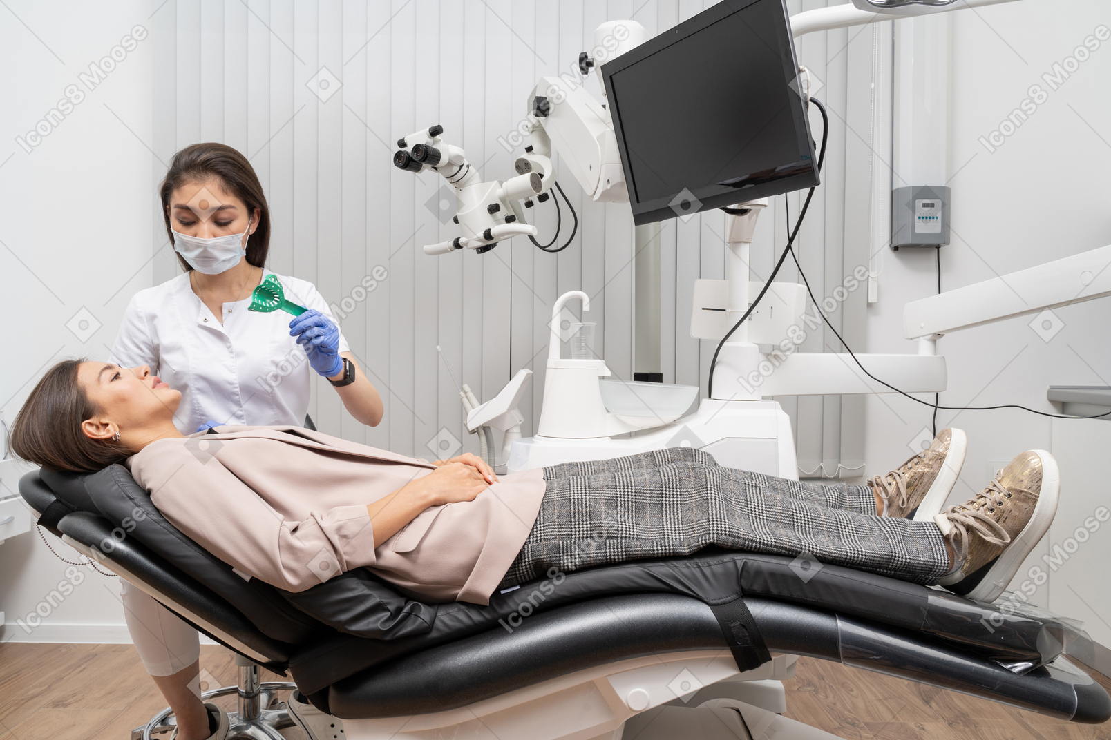 Toute la longueur d'une femme dentiste faisant un dossier dentaire à sa patiente dans une armoire d'hôpital