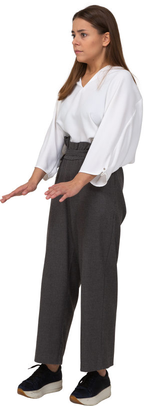 Three-quarter view of a young lady in office clothing raising hands