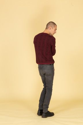 Three-quarter back view of a young man in red pullover looking aside