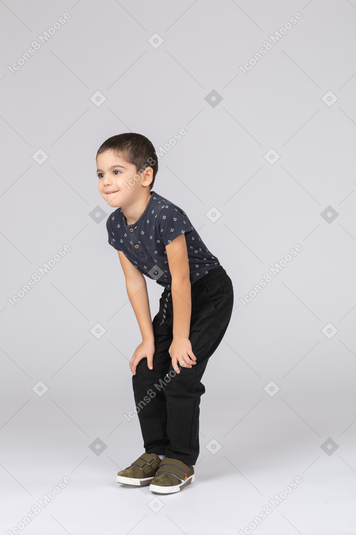 Side view of a cute boy squatting and touching knees